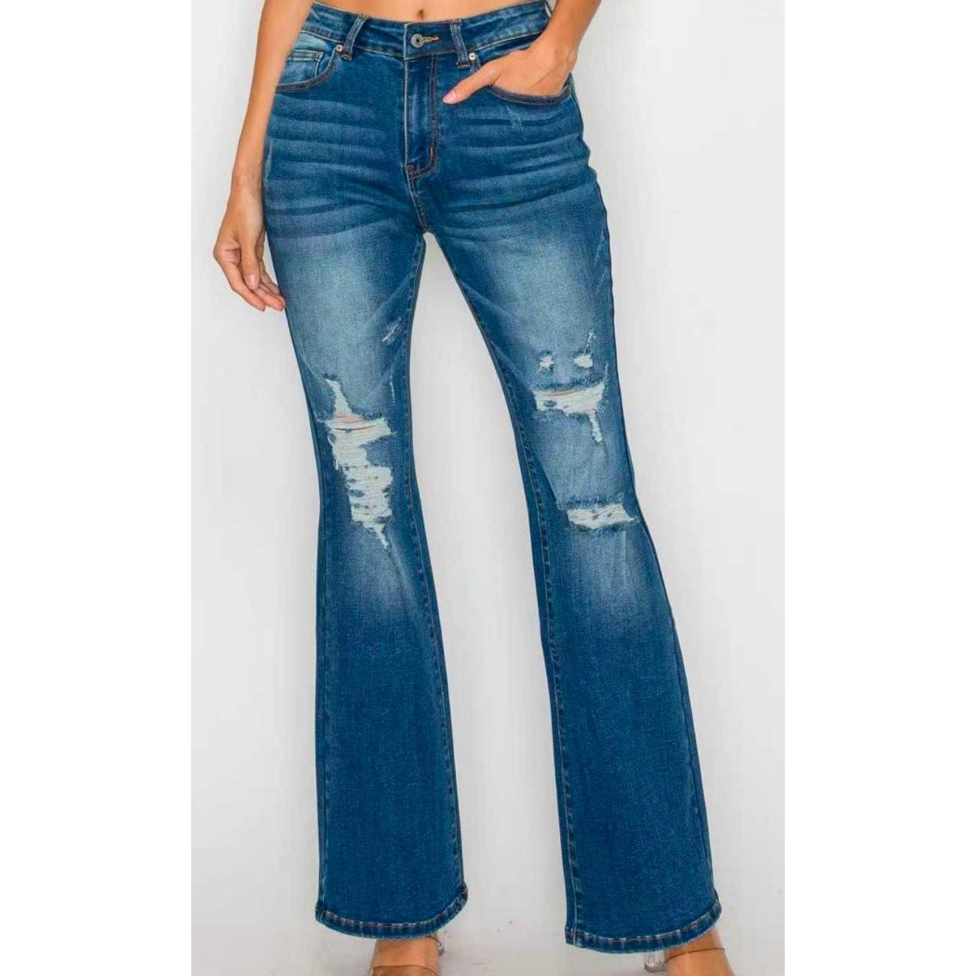 Women’s high-waist ankle jeans close-up, blue denim with worn spots and ripped hems