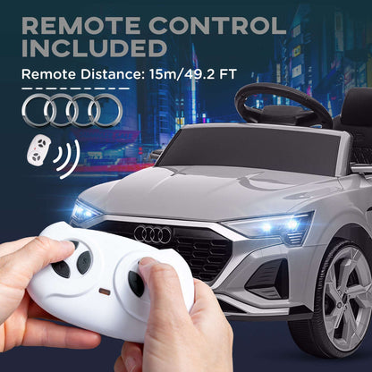 Kids ride-on car remote in hands controlling a gray car with LED headlights