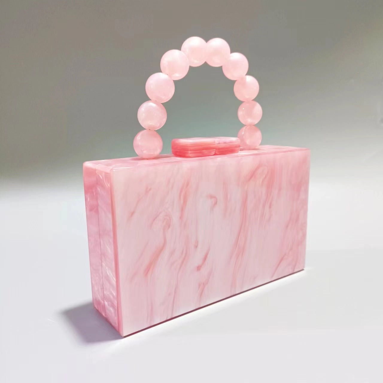 Soft pink acrylic evening bag with round beaded handle and red-toned top clasp