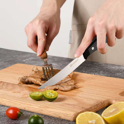 Steak knife with black handle slicing meat on a wooden cutting board