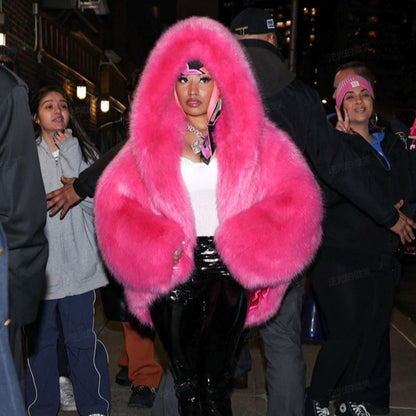 Person wearing a bright pink fur coat in an urban setting at night.