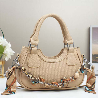 Beige braided chain crossbody handbag with top handles and textured body.