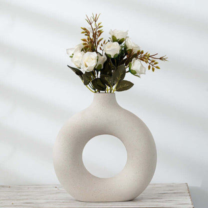 Off-white ceramic vase with circular cutout and bouquet of white flowers