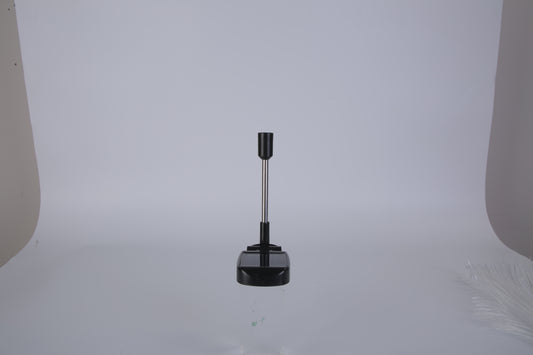 Black cylindrical object with a central rod on a white background