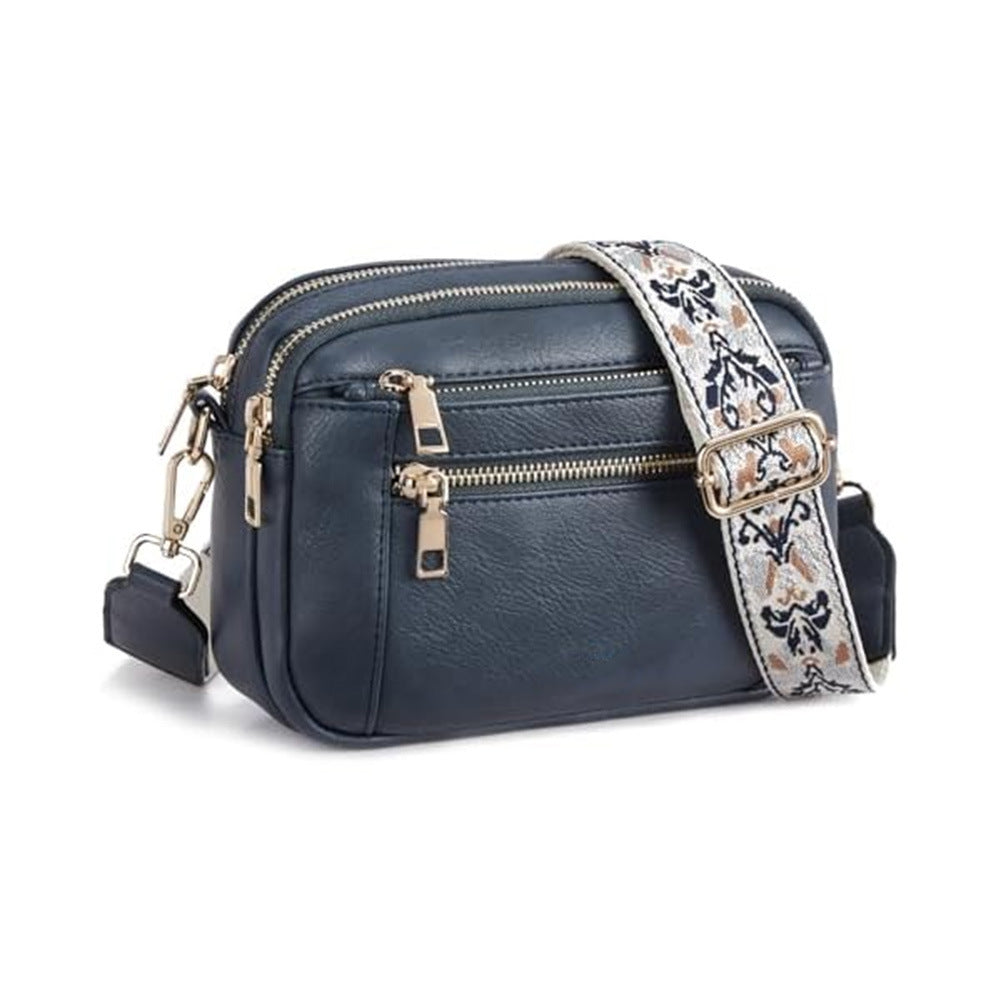 Navy blue crossbody bag with triple zippers and floral patterned shoulder strap.