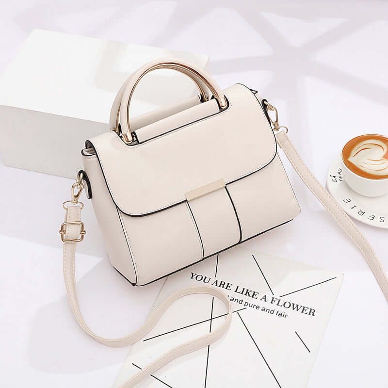 White crossbody bag with top handle, flap front, gold-tone accents, and crossbody strap