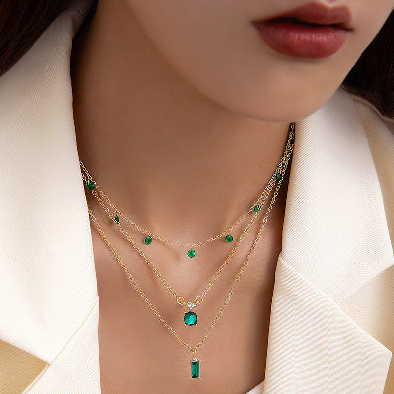 Multilayer pearl necklace with green disc charms and gold-toned chain, bar pendant