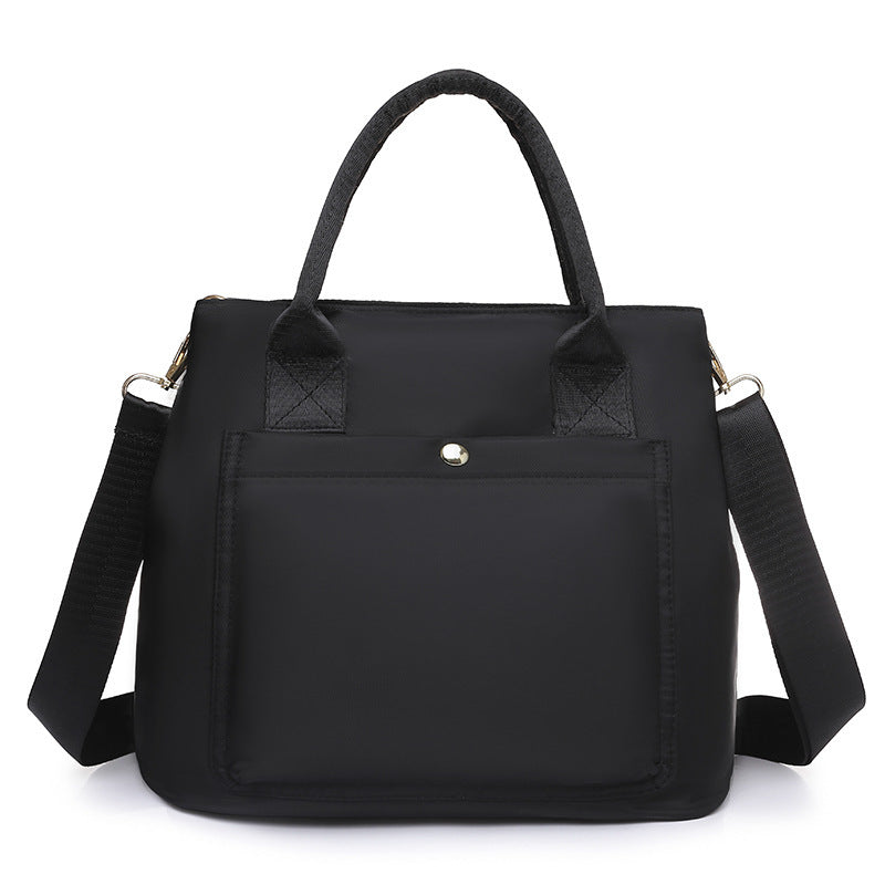 Black nylon handbag with quilted handle pads, front pocket, and crossbody strap