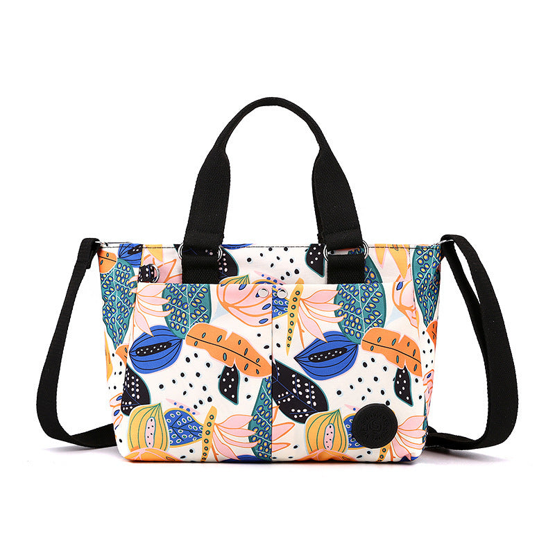 Waterproof shoulder bag with colorful leaf-and-floral print and black webbing straps