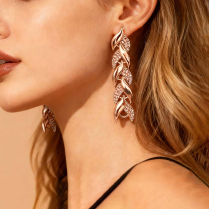 Rhinestone leaf earrings in rose gold tone with linked leaf design, close-up.
