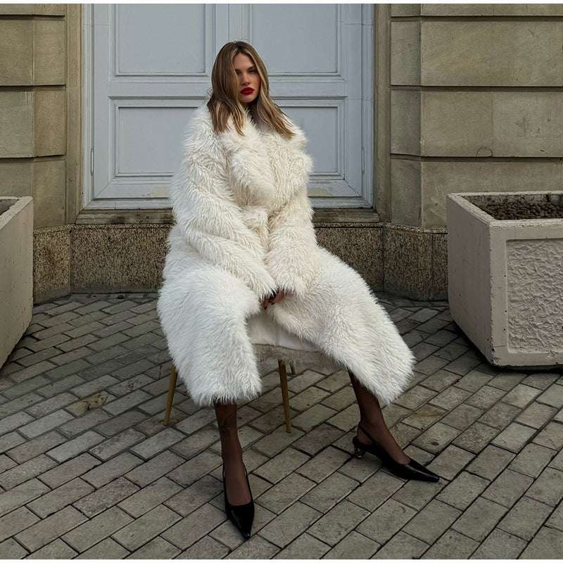 Woman in a white fur coat sitting on a chair in an urban setting.