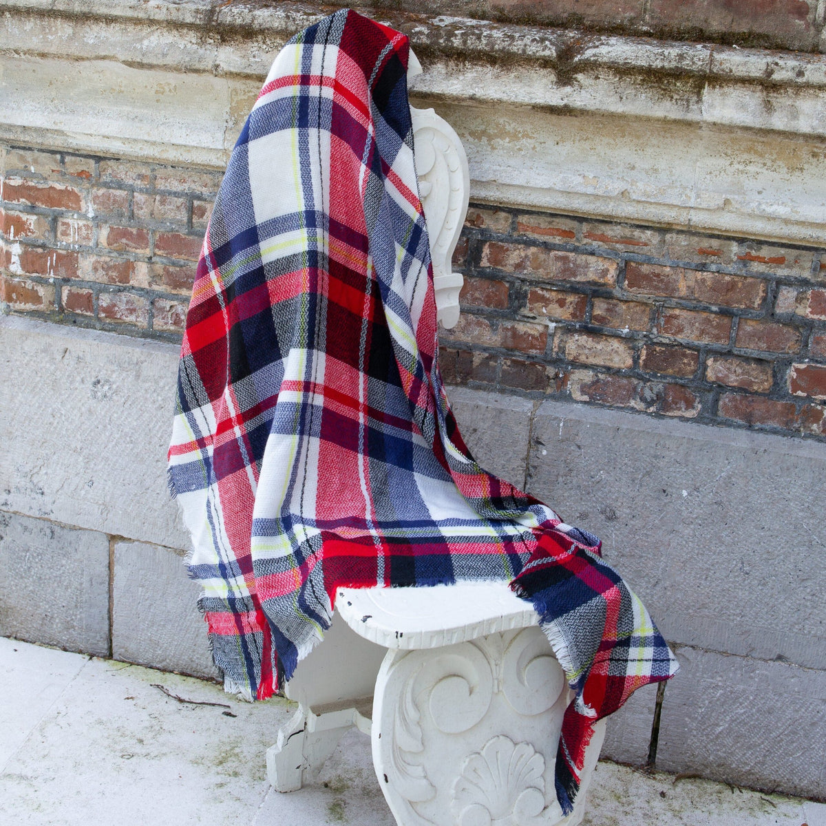 Red, navy, and white plaid scarf draped over bench, fringed edge visible