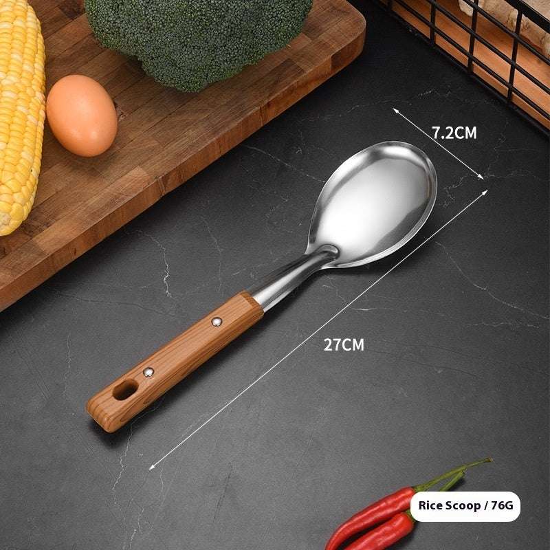 Rice scoop with wooden handle on a dark surface, surrounded by vegetables.