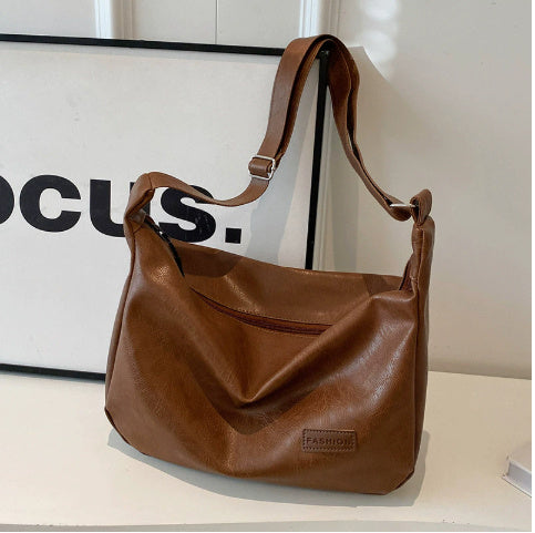 Brown hobo shoulder bag with long strap, slouch shape and front logo patch
