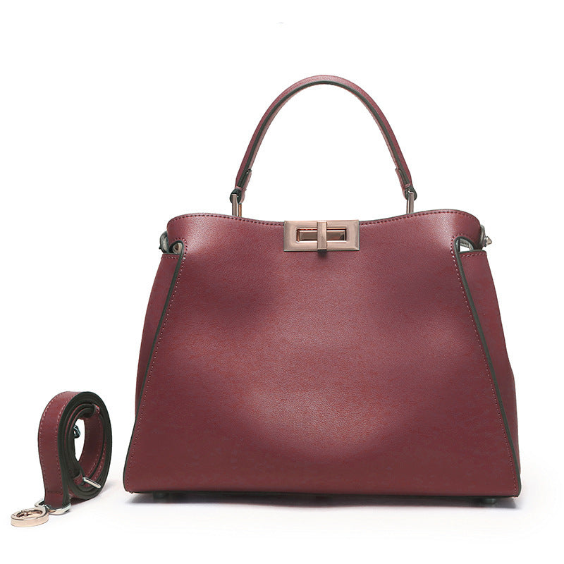 Wine-red crossbody handbag with metal clasp, top handles, and crossbody strap