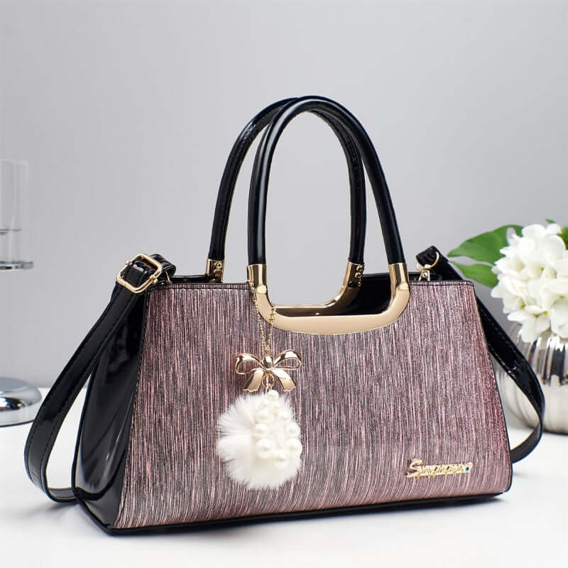Structured glitter tote handbag in mauve with black handles and white pom-pom charm