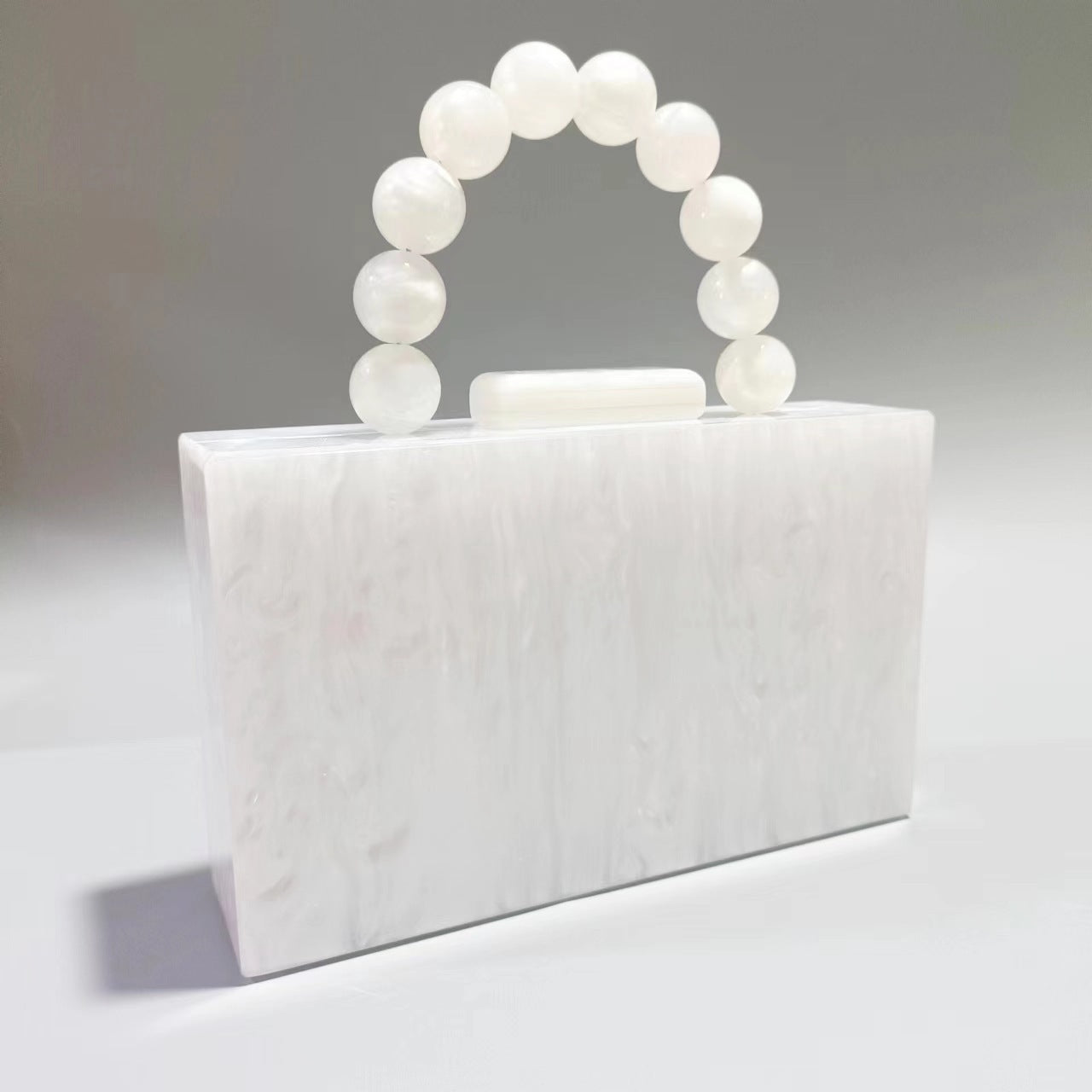 White acrylic evening bag with round beaded handle and top clasp