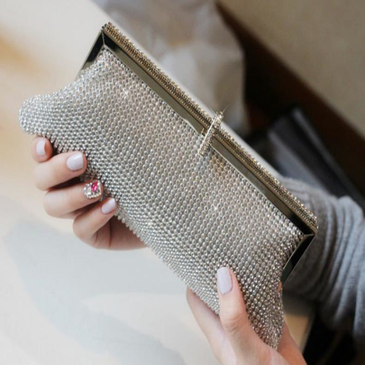 Rhinestone clutch bag with top frame, silver sparkle with gold edge held in hand