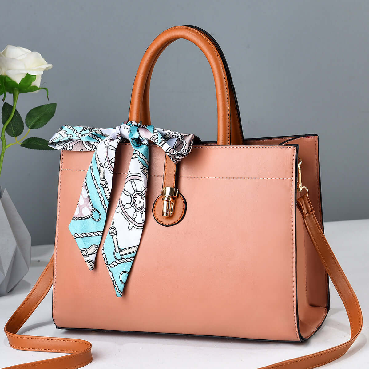 Pink large crossbody tote bag with tan handles, front clasp, and blue scarf tie