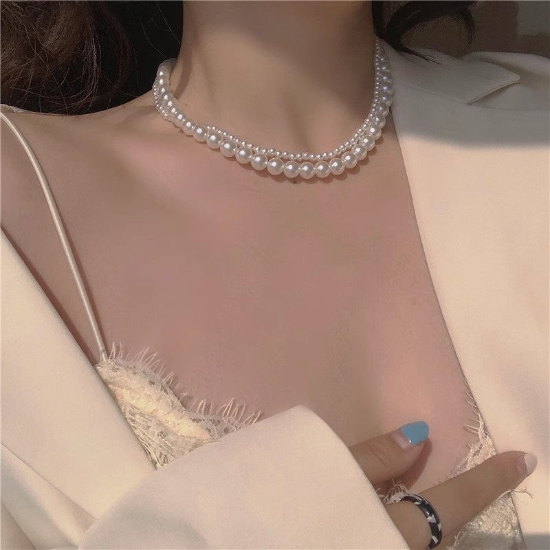 Layered pearl necklace with rounded beads across the neckline