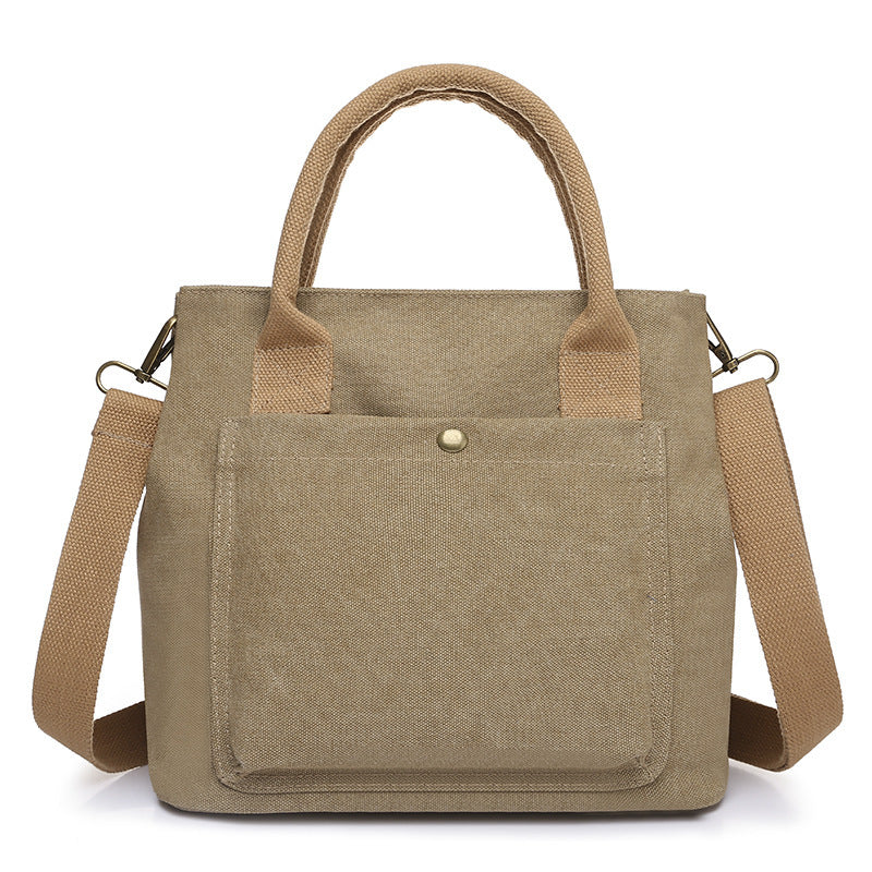 Beige canvas tote bag with front pocket, top handles, and side crossbody straps