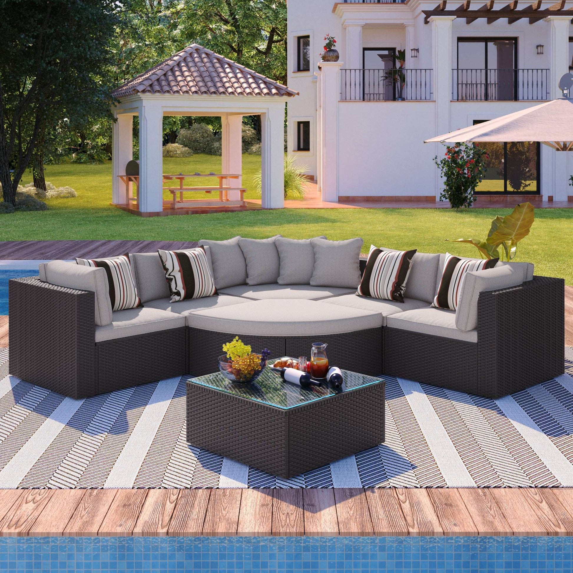 Brown wicker outdoor sectional sofa set with light gray cushions, striped pillows, and glass table
