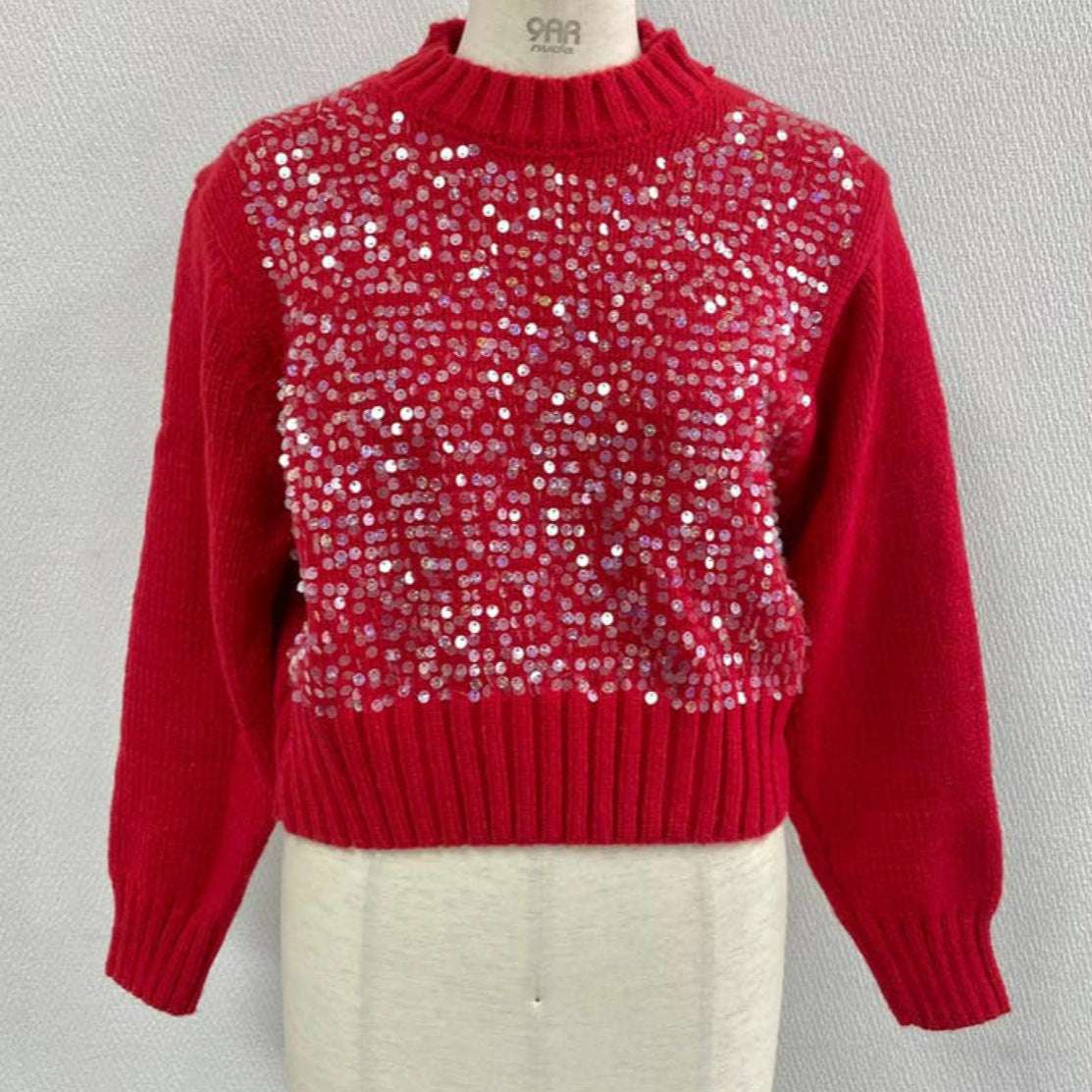 Red sweater with sequin pattern on a mannequin against a gray background