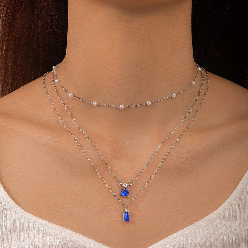 Multilayer pearl necklace with silver chain, pearl choker, and blue round and bar pendant