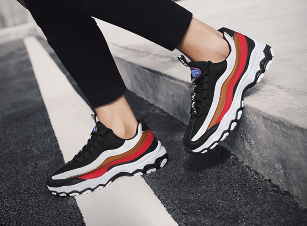 Black sneakers with red and white stripe accents, lace-up running shoe