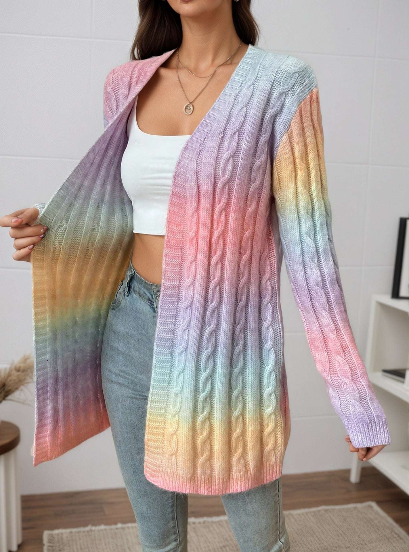 Person wearing a colorful gradient cardigan over a white top and jeans indoors.