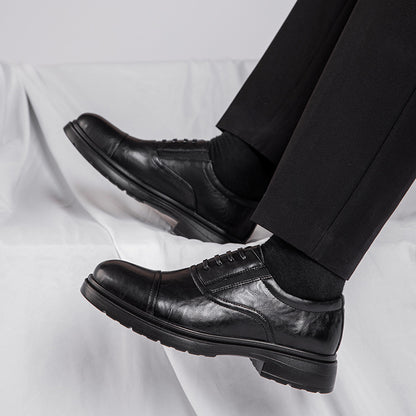 Black leather dress shoes worn with black pants on a light gray background