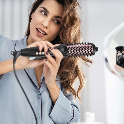 Woman using a black hot air styling brush with rose-gold bristles on her hair