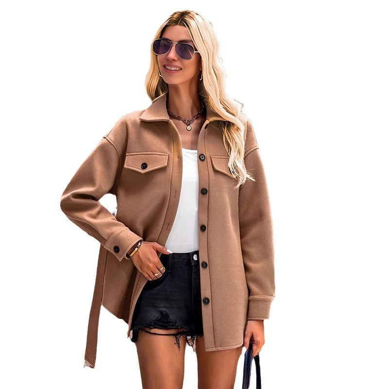 Woman wearing a beige jacket, white top, and black shorts on a white background