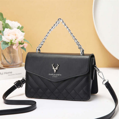 Quilted mini crossbody bag in black with silver chain strap and front flap with snap.