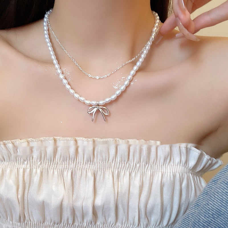 Three-layer pearl bow necklace with bow centerpiece and short chain strands