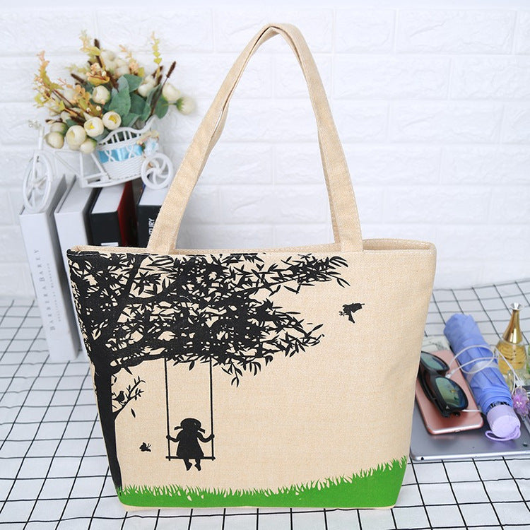 Canvas tote bag with black tree silhouette, green bottom panel, and tan handles