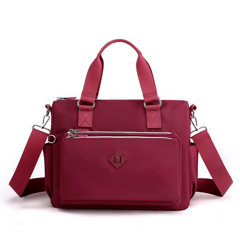 Waterproof nylon one-shoulder bag in burgundy, front zip pocket, adjustable strap