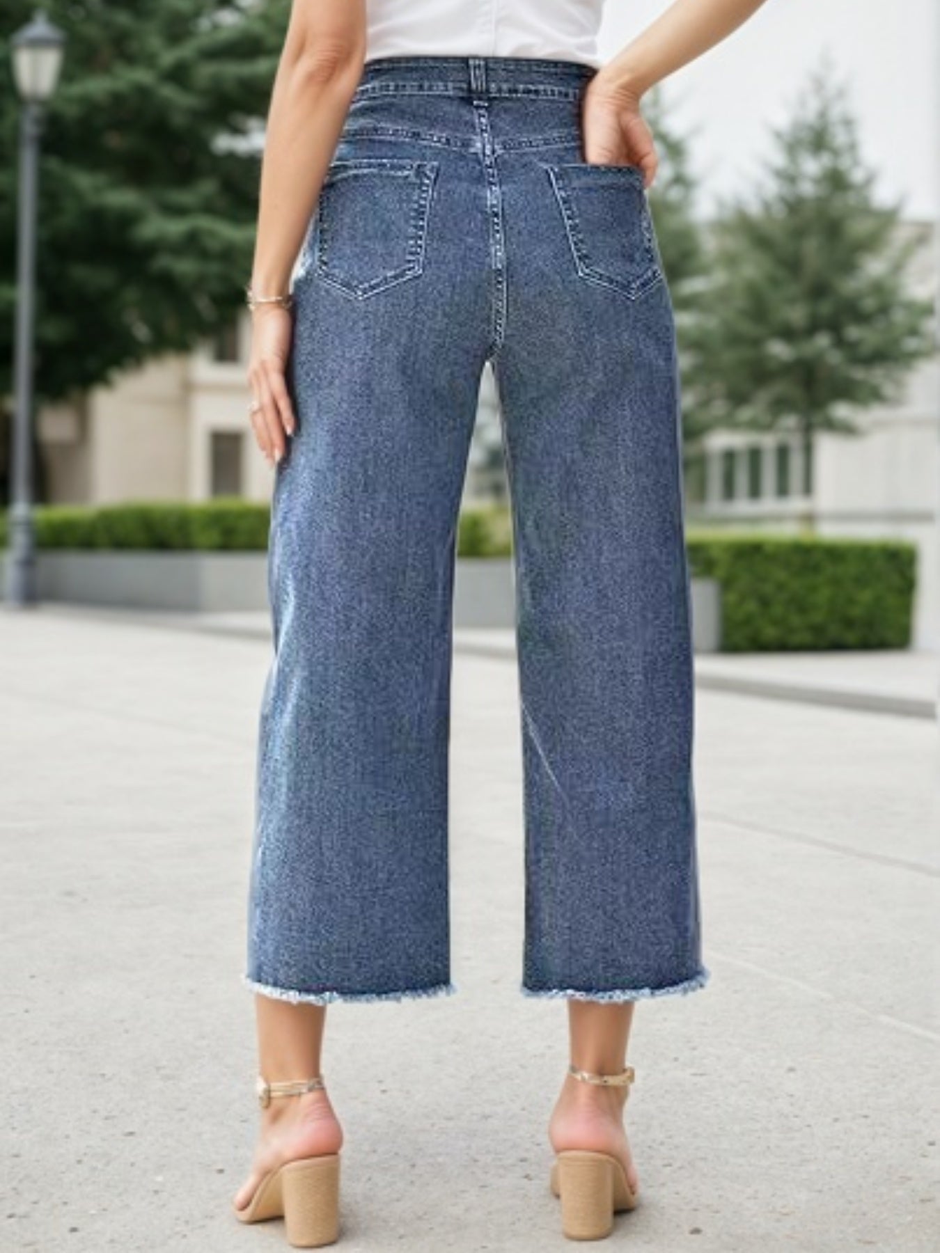 Blue wide-leg jeans with high rise, button closure, and frayed cropped hem