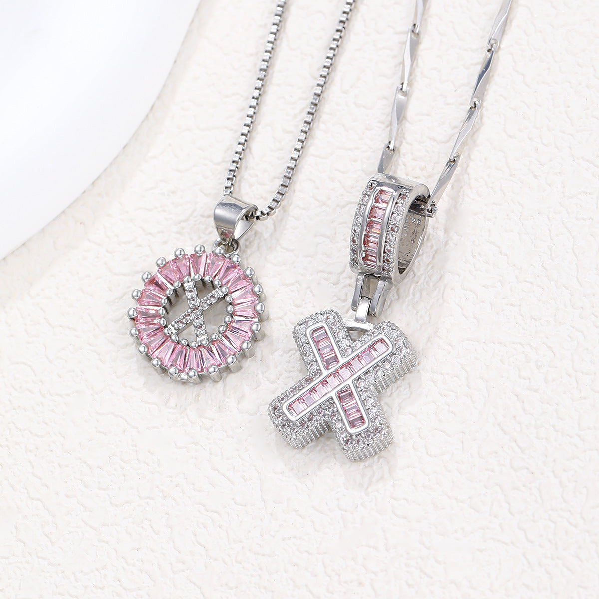 Silver-tone pendant necklace set with pink zircon rosette pendant and curved block letter pendant.