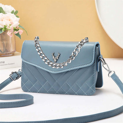 Quilted mini crossbody bag in blue with chain strap and flap front with snap closure.