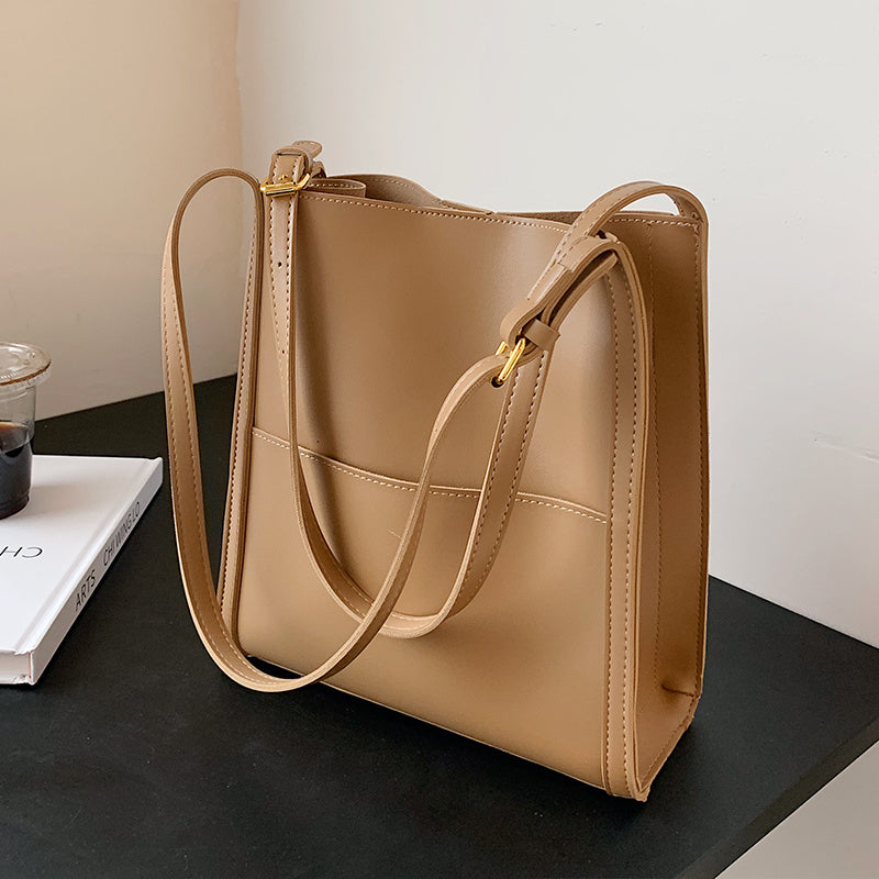 Tan leather retro shoulder bag with long straps and gold-tone hardware, large boxy shape