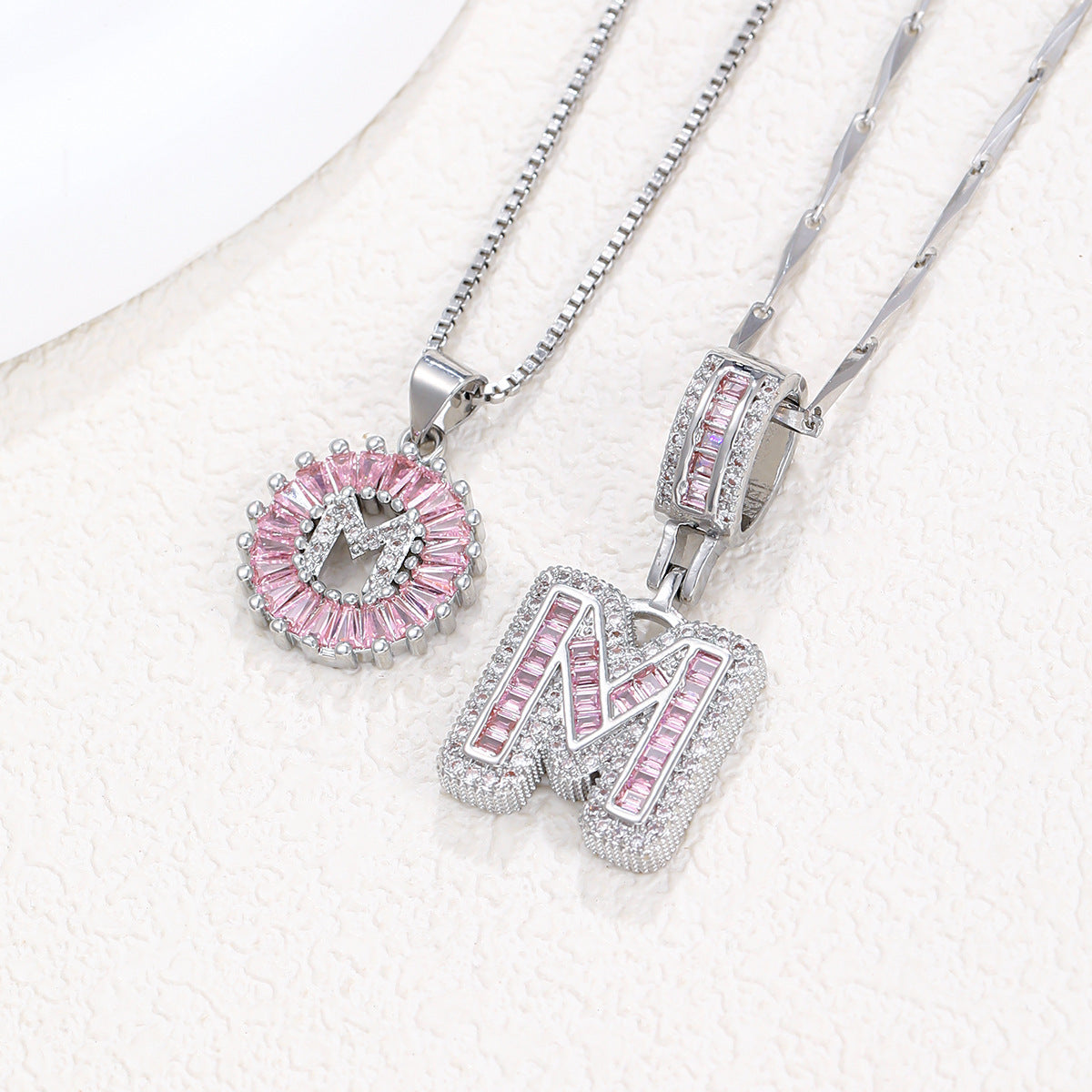 Silver pendant necklace set with pink crystal flower charm and letter charms, two chains visible