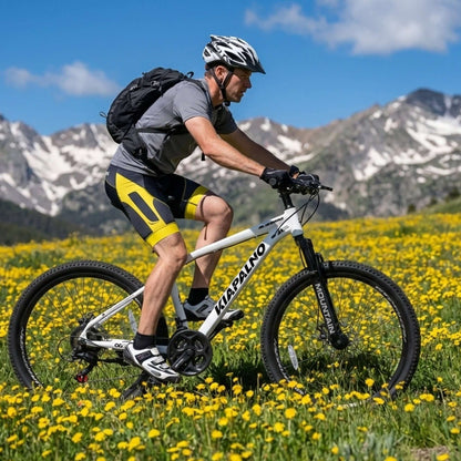 Cyclist on a white mountain bike in a flower field with mountain scenery
