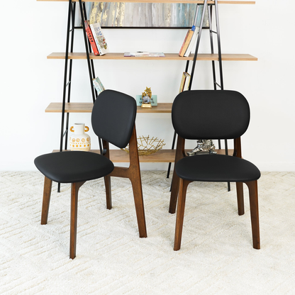 Set of 2 black leather dining chairs, symmetrical front view with rounded seats and wood legs