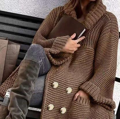 Person wearing a brown knitted coat with gold buttons, holding a brown clutch.