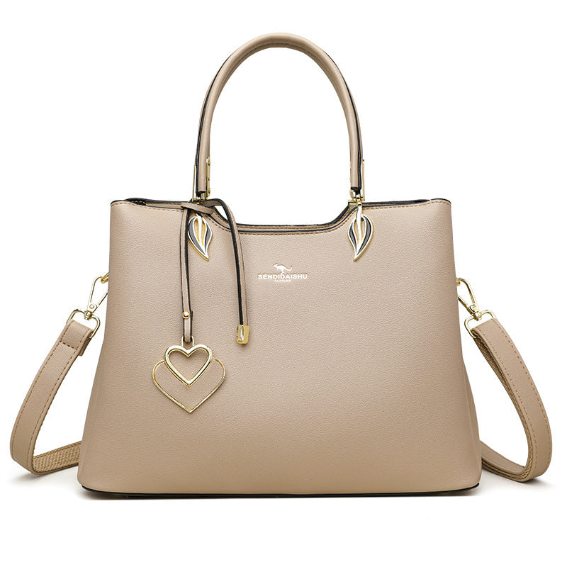Beige women’s shoulder bag with top handles, crossbody straps, and gold heart decoration