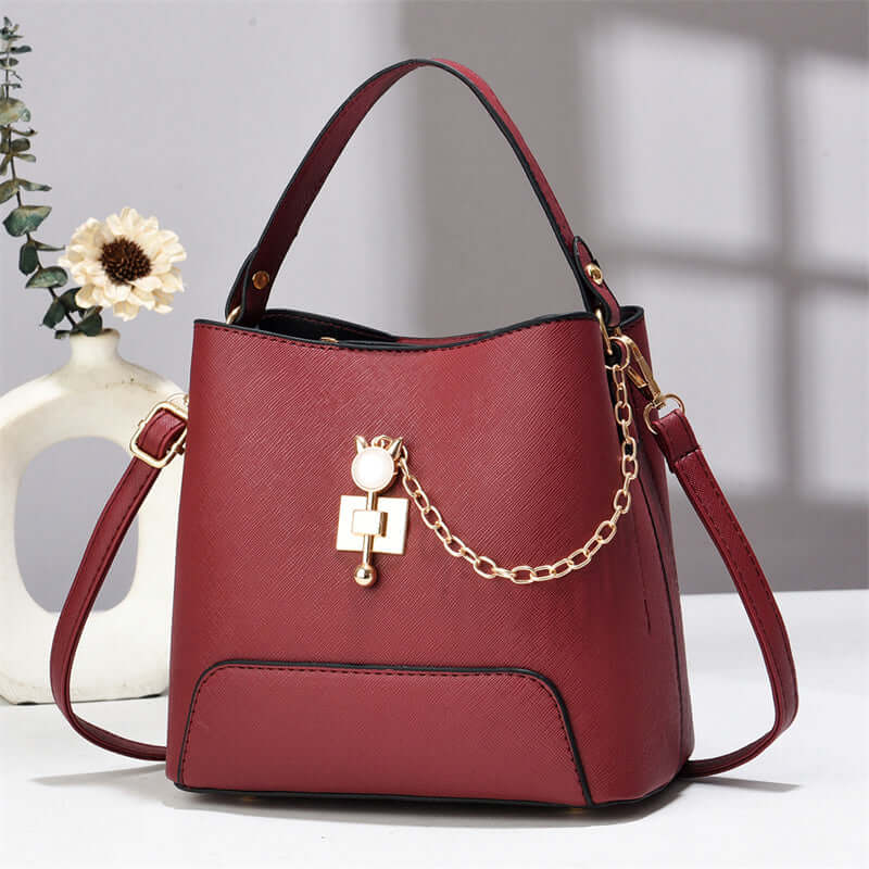Red PU leather bucket bag with top handle, shoulder strap, and gold chain lock charm