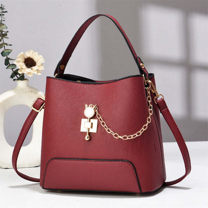 Red PU leather bucket bag with top handle, shoulder strap, and gold chain lock charm