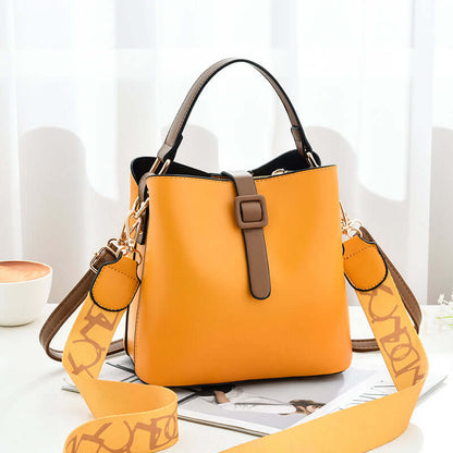 Orange PU leather bucket bag with top handles, front buckle tab, and patterned crossbody strap