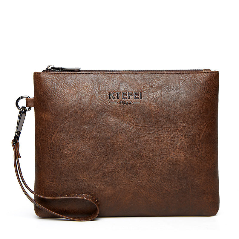 Men's dark brown clutch bag with zip top, logo, and wrist strap